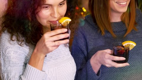 Young women at home party, drink mulled wine and enjoy carefree time. Pastime indoors concept.