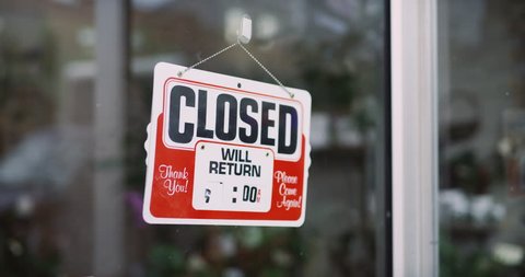 Store owner turning CLOSED sign to OPEN in exterior boutique plant shop with soft day lighting. Close up shot on 4k RED camera.