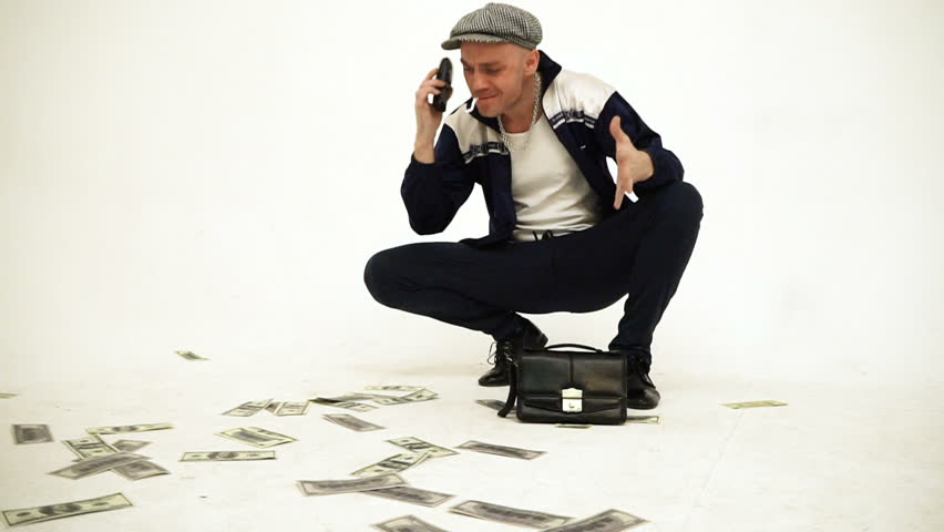 An old fashioned squatting slav in a tweed cap with a leather purse talking angrily on phone with money on the floor Royalty-Free Stock Footage #1018635475