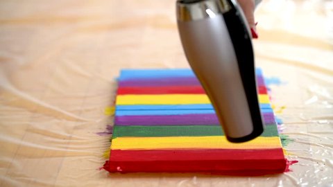 Female artist painting a rainbow with acrylic colors on canvas, hoe made art, DIY tutorial, colorful, drying color with hair dryer