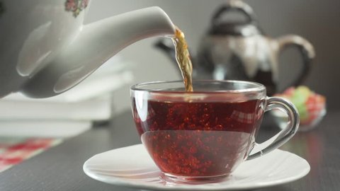 Tea being poured into glass transparent tea cup. Cup of tea.
Sweets, hot tea and teapot. Ceramic teapot and glass teacup closeup. Slow motion
