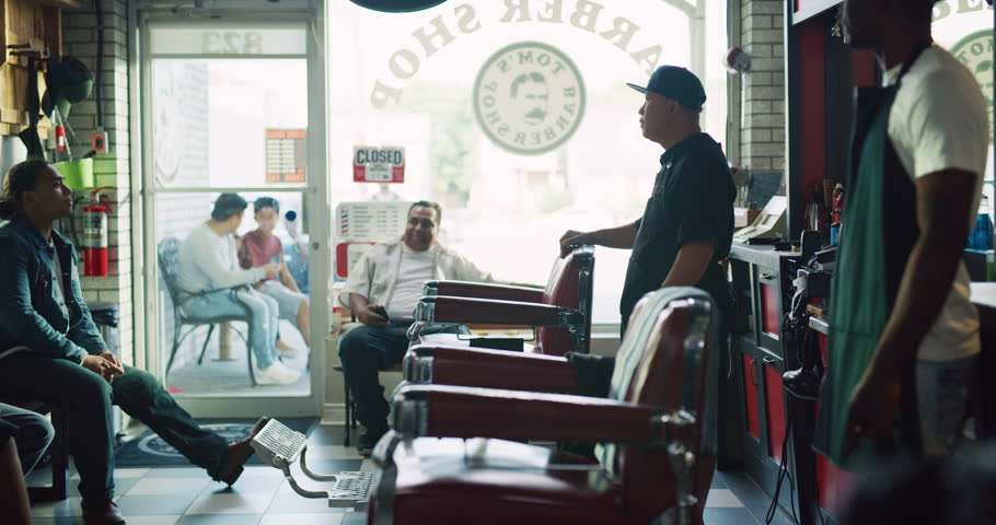Happy cool male customers sitting in barber chair in interior hipster barbershop with soft day lighting. Wide shot on 4k RED camera on a gimbal.  Royalty-Free Stock Footage #1018646659