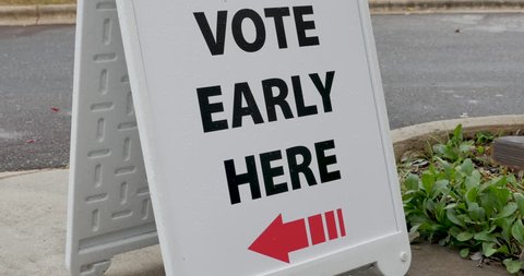 Vote early here sandwich board sign with an arrow pointing to the left to the voting location