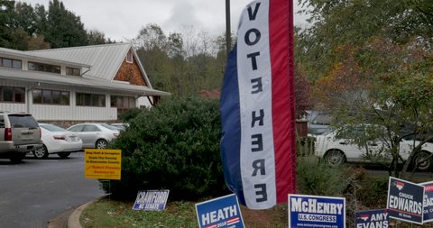 ASHEVILLE, NC, USA - OCTOBER 26 2018 - Close up of a Vote Here flag blowing in the wind at the entrance to a voting location - establishing shot
