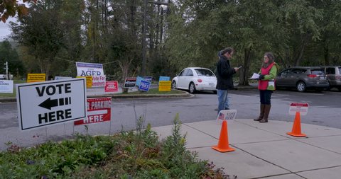 ASHEVILLE, NC, USA - OCTOBER 26 2018 - Man talking to a woman in front of a voting location getting voter information just in front of the no electioneering sign