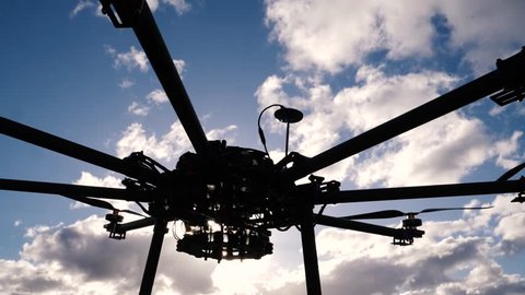 Siloutte of large octocopter drone in a paddock