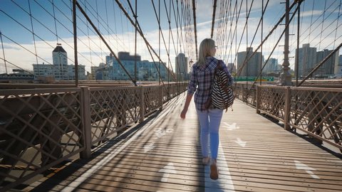 Carefree tourist walks along the Brooklyn Bridge towards Brooklyn. Morning in New York