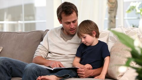 Nice father reading a story to his young son: stockvideo