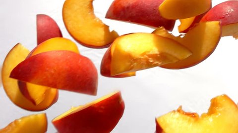 Slices of peach fly close-up on white background in slow motion