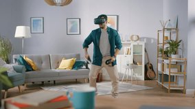 Energetic Young Man Wearing Virtual Reality Headset and Holding Controllers Plays in a Video Game at Home. Man Playing VR Shooter in the Middle of Living Room.
