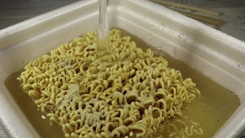 Someone pouring boiled water into the instant noodles