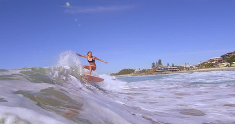 Surfing is not a sport, it is a lifestyle. The perfect clip you need of a surfer riding her surfboard on a wave on a beautiful day. Medium shot 4K RED camera. Buy it now and get caught in the waves