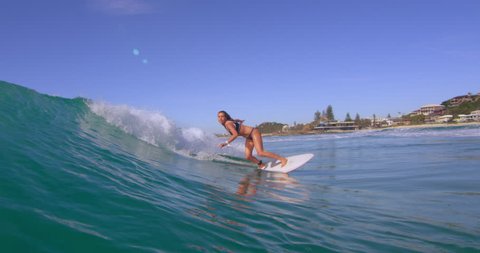 Athletic blonde woman surfing a large ocean wave and having fun in Australian beach with bright day lighting. Wide shot on 4k RED camera.