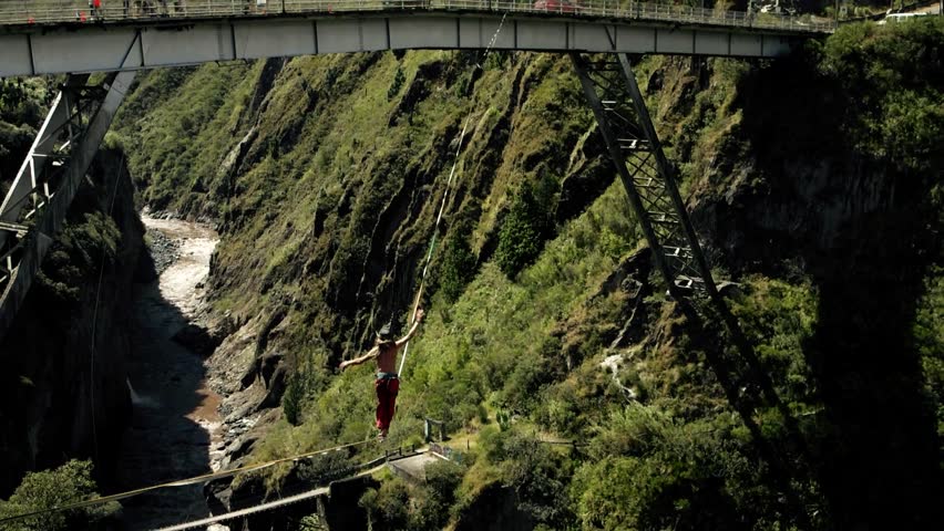 young male falling on slack line or tightrope over forest in ecuador