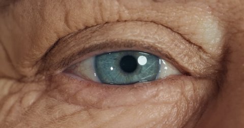 close up blue eye opening old woman blinking macro aging beauty optometry concept