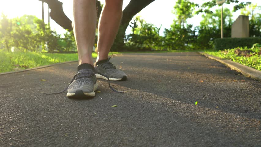 Closeup of feet of man runner getting ready tying running shoes before running in park exercising outdoors Royalty-Free Stock Footage #1018692874