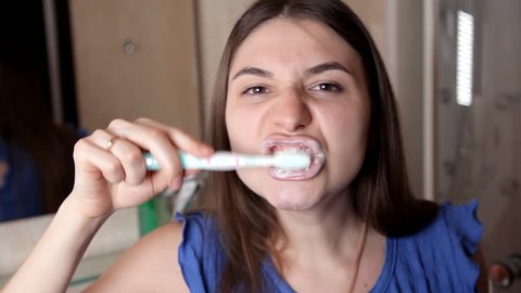 A young girl stands in front of a bathroom mirror and cleans her teeth. healthy teeth