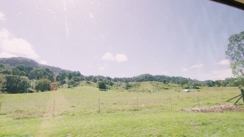 View of countryside passing by from vintage car window with young happy woman sitting, smiling in the front seat in Australia. Shot in natural sunlight, medium shot on 4K RED camera.