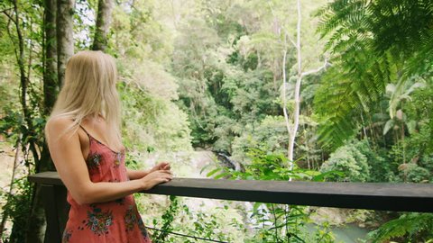 Young, happy diverse couple look at each other lovingly and hug with spectacular view of forest, stream and waterfall in the background, in Australia in natural sunlight. Medium shot on 4k RED camera