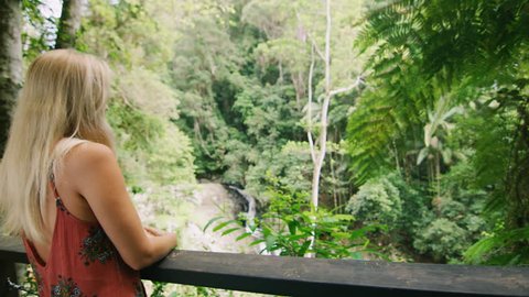 Young, happy diverse couple look at each other lovingly and hug with spectacular view of forest, stream and waterfall in the background, in Australia in natural sunlight. Medium shot on 4k RED camera