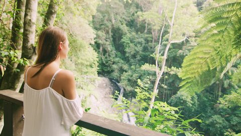 Young, happy couple look at each other lovingly and hug with spectacular view of forest, stream and waterfall in the background, in Australia in natural sunlight. Medium shot on 4K RED camera.