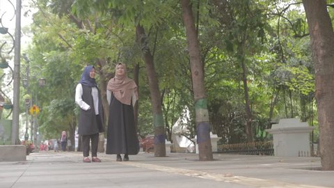 Two young south east asian muslim female walking in the street