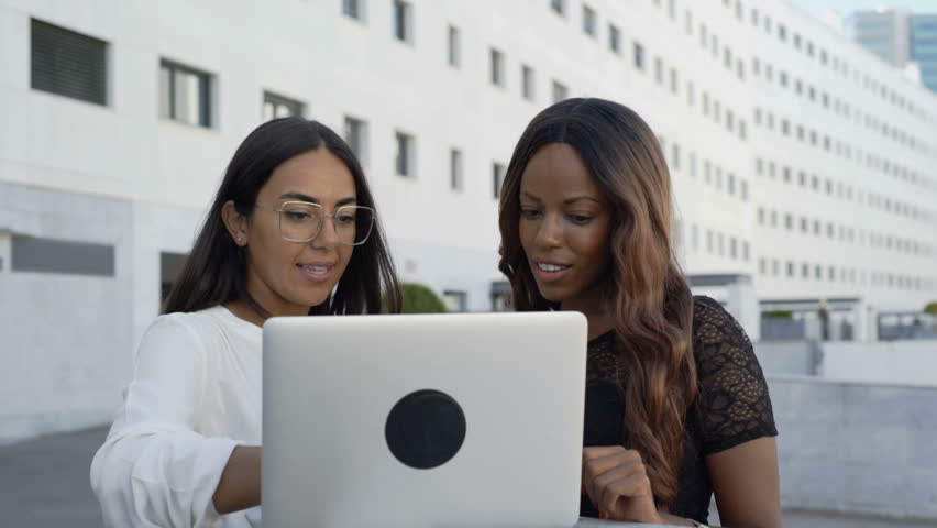 Multicultural businesswomen talking about project with laptop in city. Professional Latin and African American colleagues brainstorming with digital device near office building. Brainstorm concept
 Royalty-Free Stock Footage #1018710376