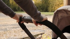 Modern stroller handle in mother hands slow motion footage