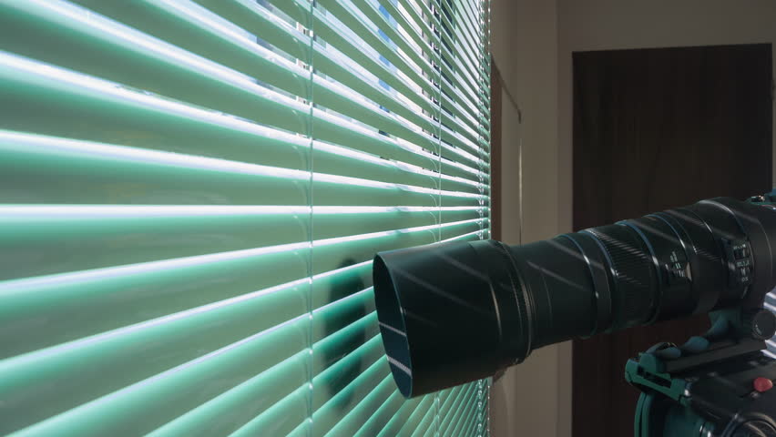 Focused male paparazzi doing surveillance by camera and using talkie walkie