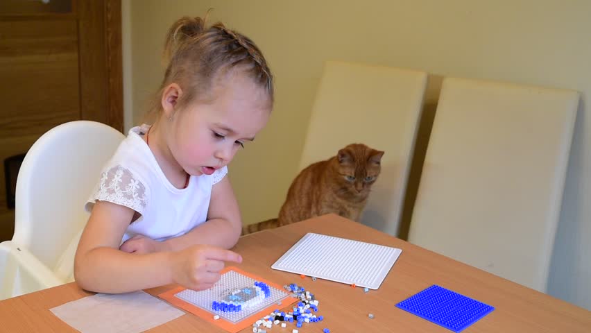 Little girl kid playing ironing plastic beads at home