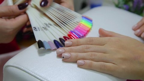 Nail polish testers and young woman manicured hands. Girl choosing perfect nail varnish color.