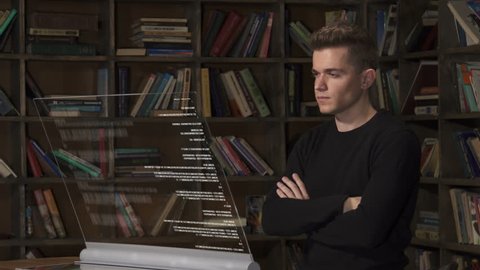 Caucasian male app tester looking at program code analyzed by artificial intelligence. Java code appearing on transparent screen. Programmer education at library.