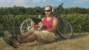 A man plays video games. Cyclist on vacation playing video games on the tablet.
