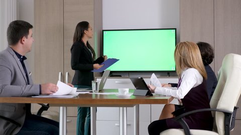 Businesswoman talking in the conference room in front of green screen chroma mock up TV. Dolly slider 4K footage