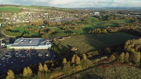 Aerial footage over the town of Bathgate in West Lothian, Scotland. Approaching the Railway station as a passenger train departs..