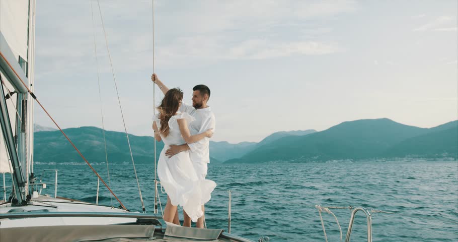 Couple in love relaxing on the yacht. Wind blows woman