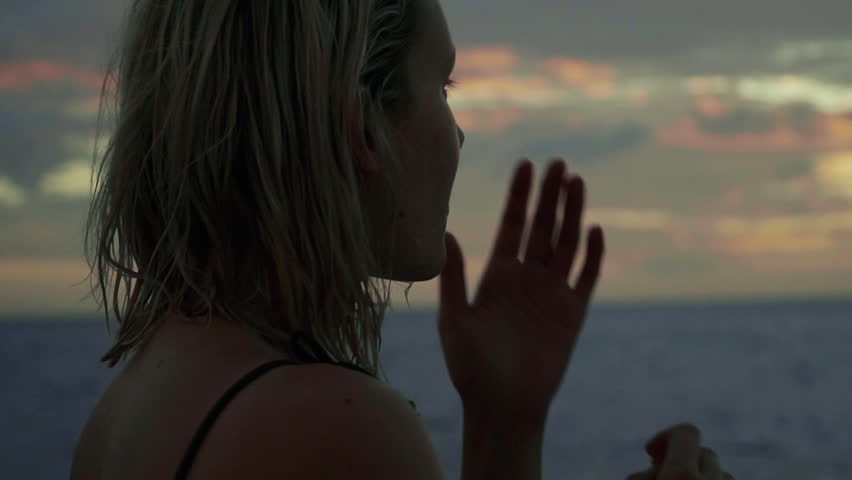 SLOW MOTION: Close up shot of a young blonde woman dancing and looking at the sunset - sunrise from a boat in the middle of an ocean - sea. Summer Vacation in Middle America.