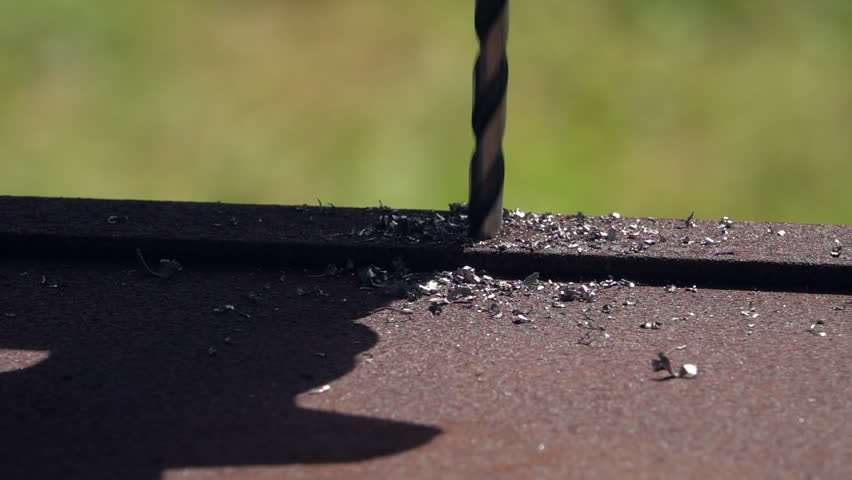 Slow motion of iron boring with flying drillings away and unstable detail. Bore in holder of hand drill on green garden background. Detailed metalwork with grunge rusty texture close up., an Industrial Video by andamanec