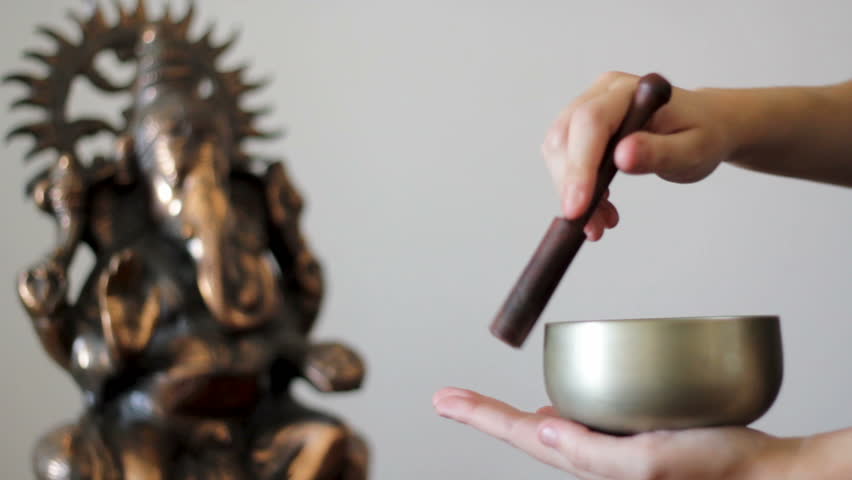 Playing a Tibetan Singing Bowl with Ganesh statue on the background. With sound Royalty-Free Stock Footage #1018752013
