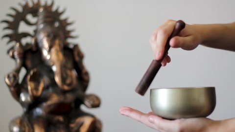 Playing a Tibetan Singing Bowl with Ganesh statue on the background. With sound