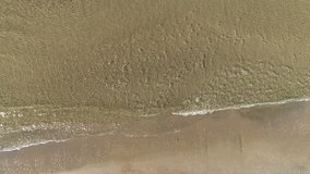 Aerial top view of sand beach with small waves.