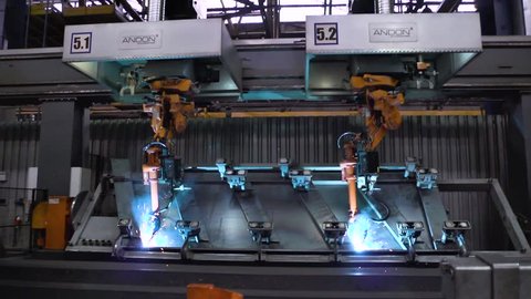 Welding robots movement in car factory. Scene. Movement of robot when welding with sparks at factory of auto parts