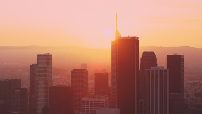 Aerial view of colorful sunset behind tall buildings and skyscrapers of downtown Los Angeles, California, with bright sunset lighting. Best Los Angeles Aerial shot. Wide shot on 4k RED camera