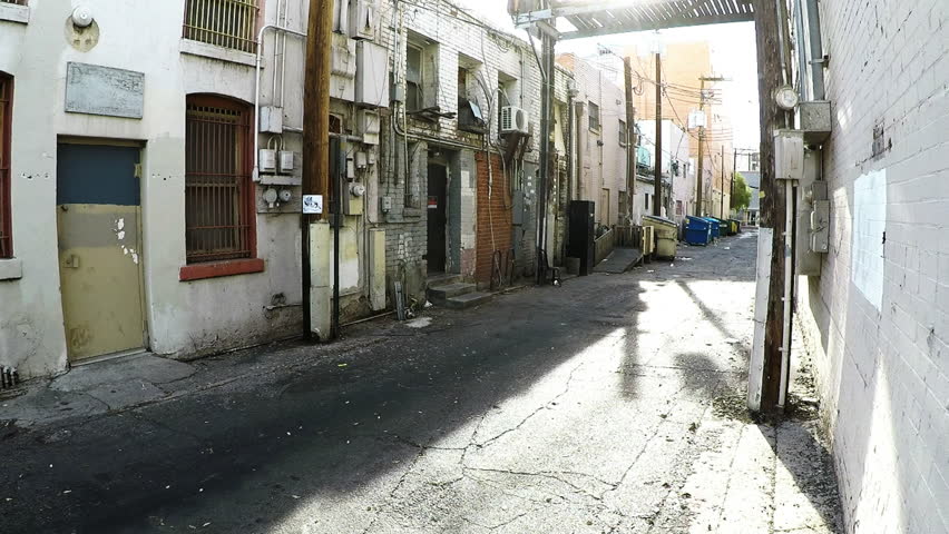 Tucson, AZ/USA - April 26, 2018: Zoom shot of a generic back alley in downtown Tucson Arizona. Clip reveals a grungy view of service entrances, utility connections and dumpsters at rear access points.