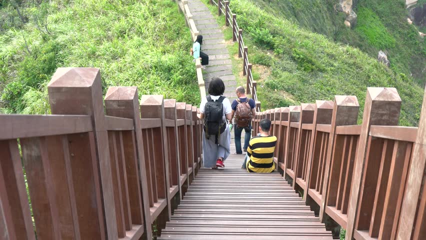 Keelung, Taiwan - 06 13 2018: Keelung, Taiwan, June 2018 - Tourists walking down a path with stairs on a green cliff.