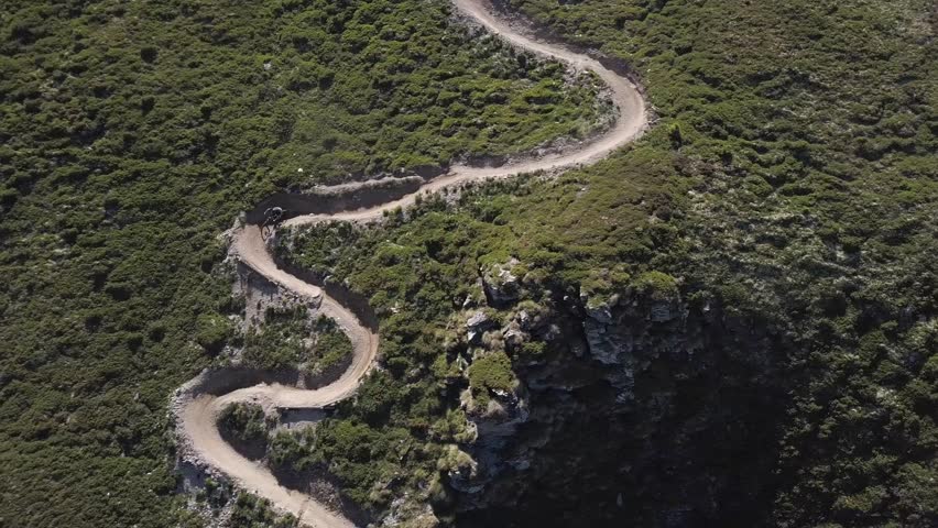 Flying above a winding dirt trail with mountain bikers in Verbier, Switzerland.