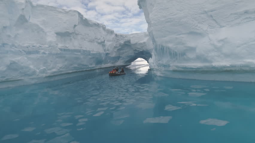 Sailing Boat Among Icebergs In Antarctica Polar Ocean. Epic Winter Landscape. Touristic Zodiac Boat Takes An Extreme Cruise. Crystal Clear Blue Ocean Water And Ice Mountains. 4k Footage.