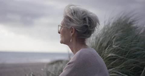 Mature lady sitting and looking out at ocean contemplating life