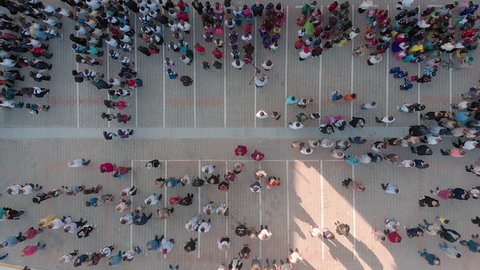 Rotating top view of a diverse crowd in a schoolyard.