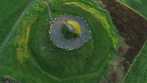 Cairnpapple Hill, near Torphicen in West Lothian, Scotland. A Neolithic ceremonial henge monument. Aerial footage circling the mound, brightly lit by a low sun on one side.